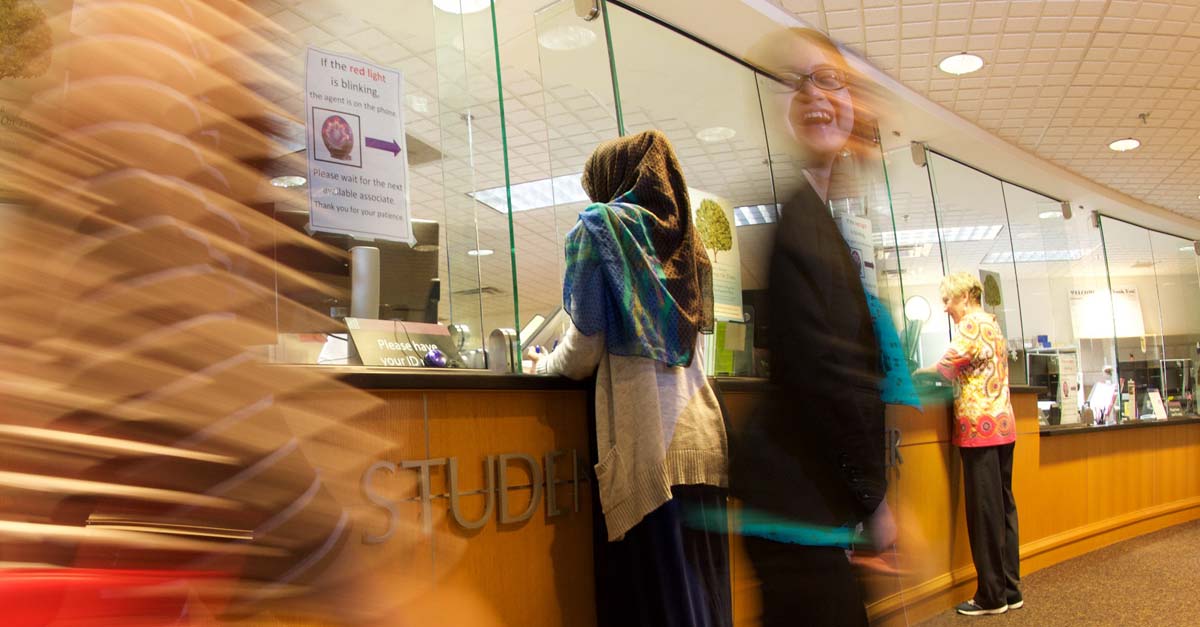 A group of students is blurred as they move through the lobby of a building.
