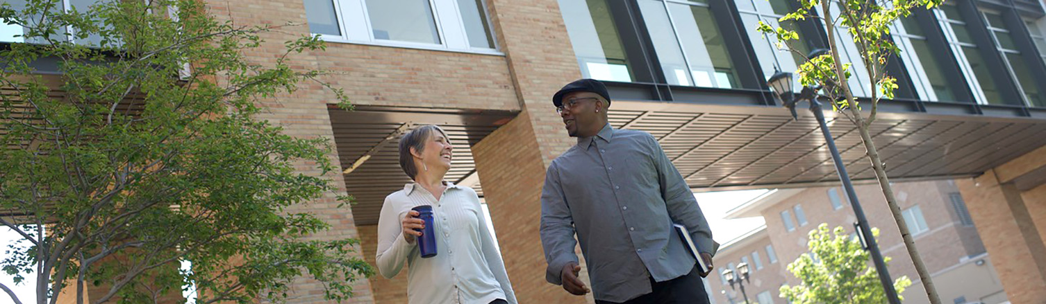 A white woman and a Black man are talking as they walk on Metro State's campus.>
			</div>
			<div class=