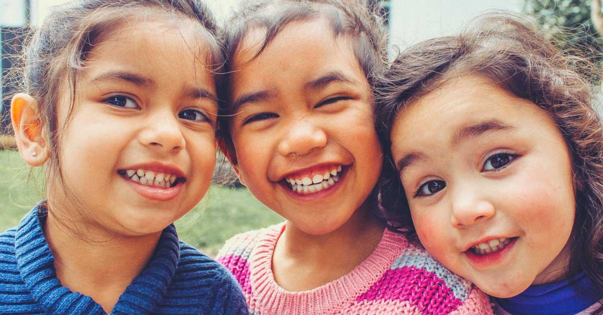 Three girls smiling and looking at the camera.