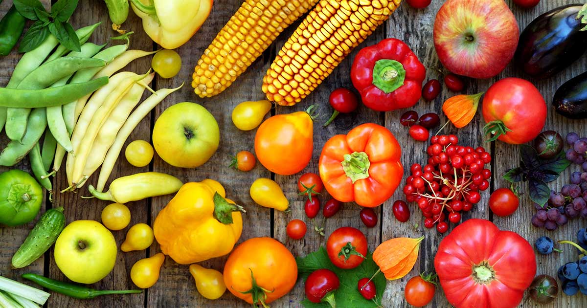 A photo of various fruits and vegetables that are arranged by color to form a spectrum.