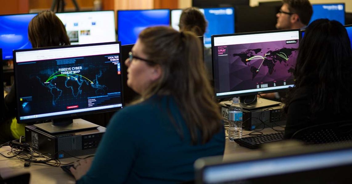 A white woman sits at a computer terminal in a classroom.