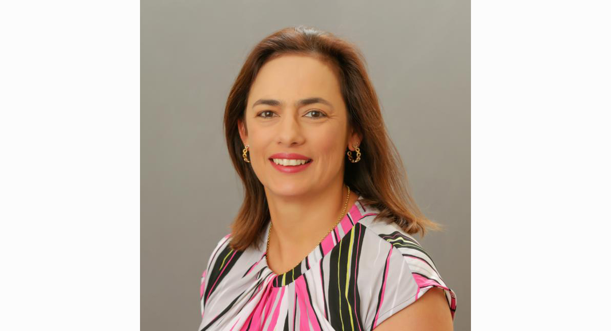 A woman in a multi-colored top poses for a portrait