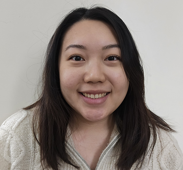 A portrait of a person with long dark hair wearing a white sweater