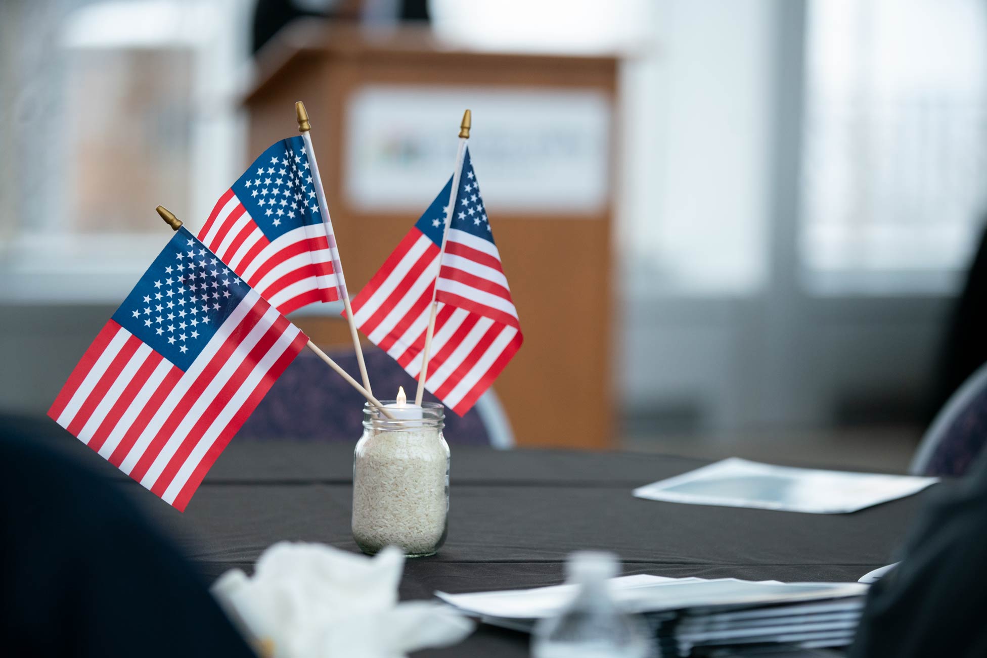 a table with a white vase and three small American flags arrayed
