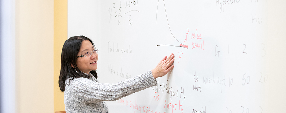 An instructor demonstrates a problem on the whiteboard in class