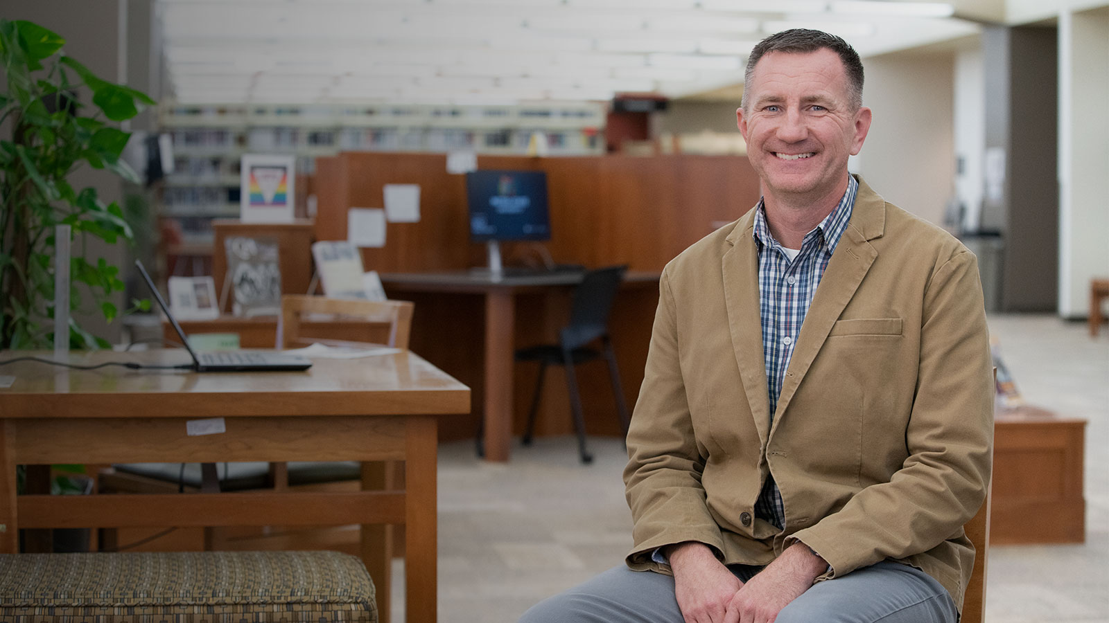 Student in tan jacket sits in the library