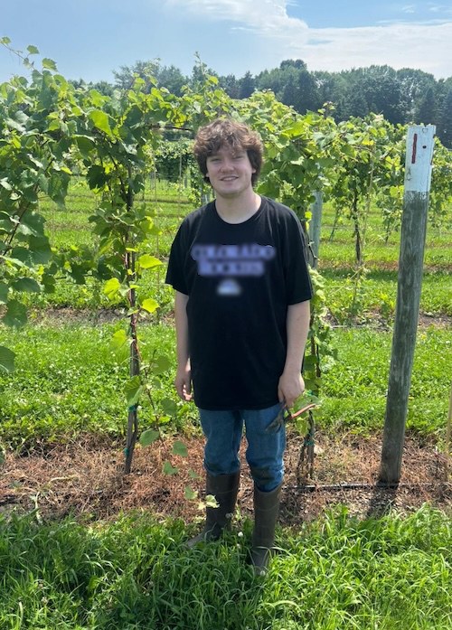Hans Arvidson-Hicks posing in front of a vineyard