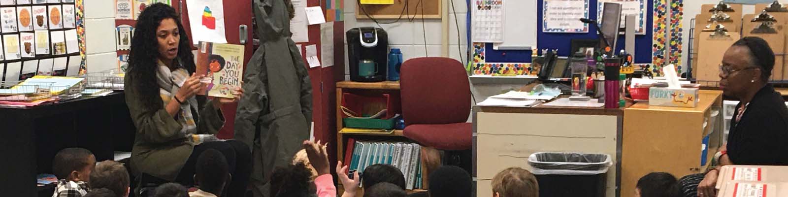 Teacher reading a book in front of classroom of children.