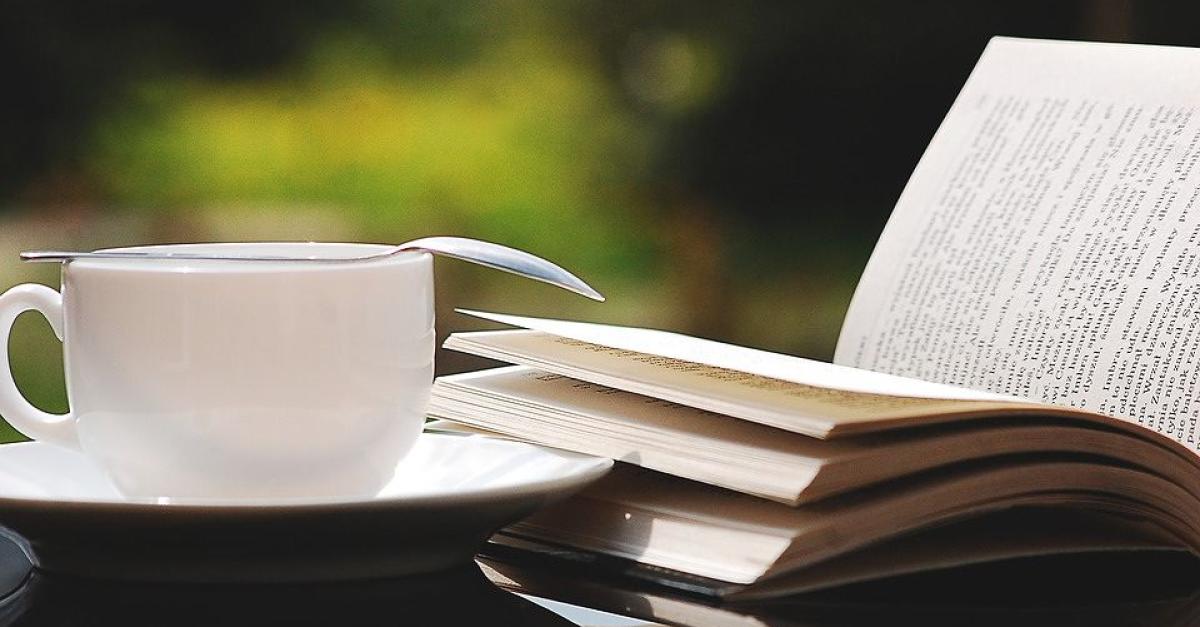 A coffee cup next to an open book