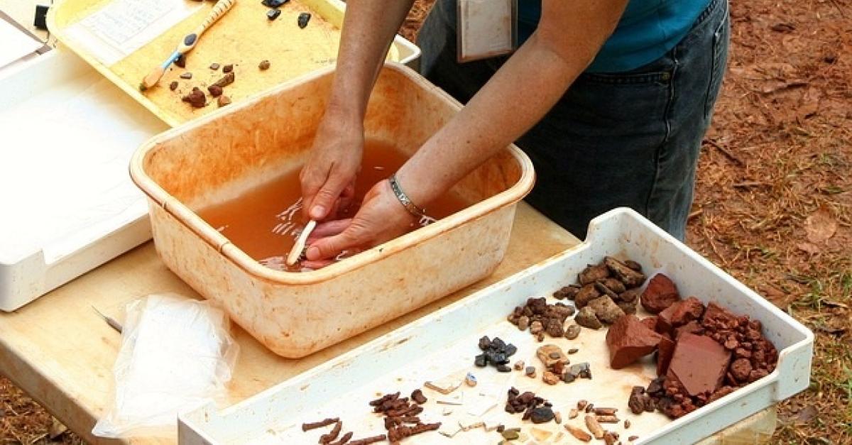 Someone washing stone at an archaeology dig