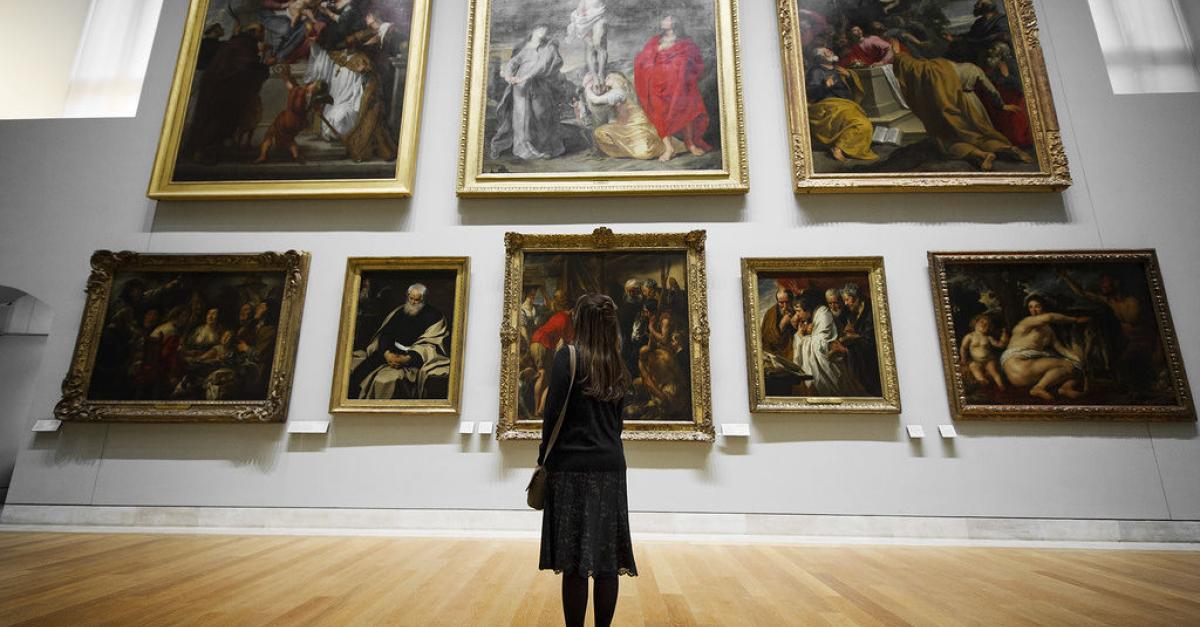 Woman looking at wall of art.