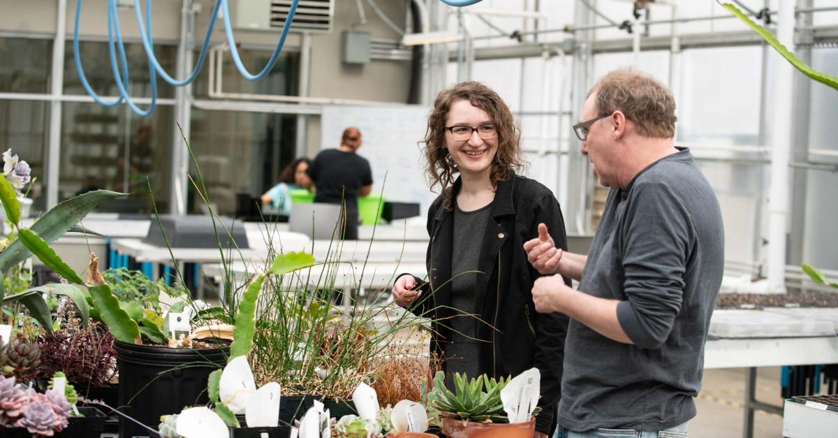 an instructor and student talking in a greenhouse