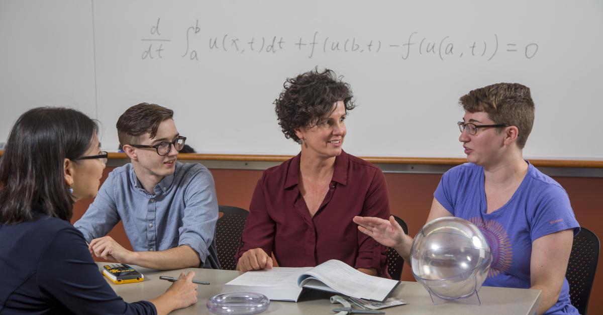 faculty and students in conversation at a table