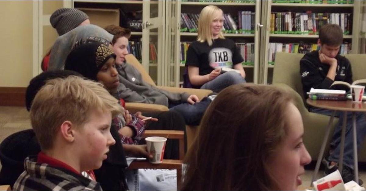 Teenagers sitting in a half circle with books open.