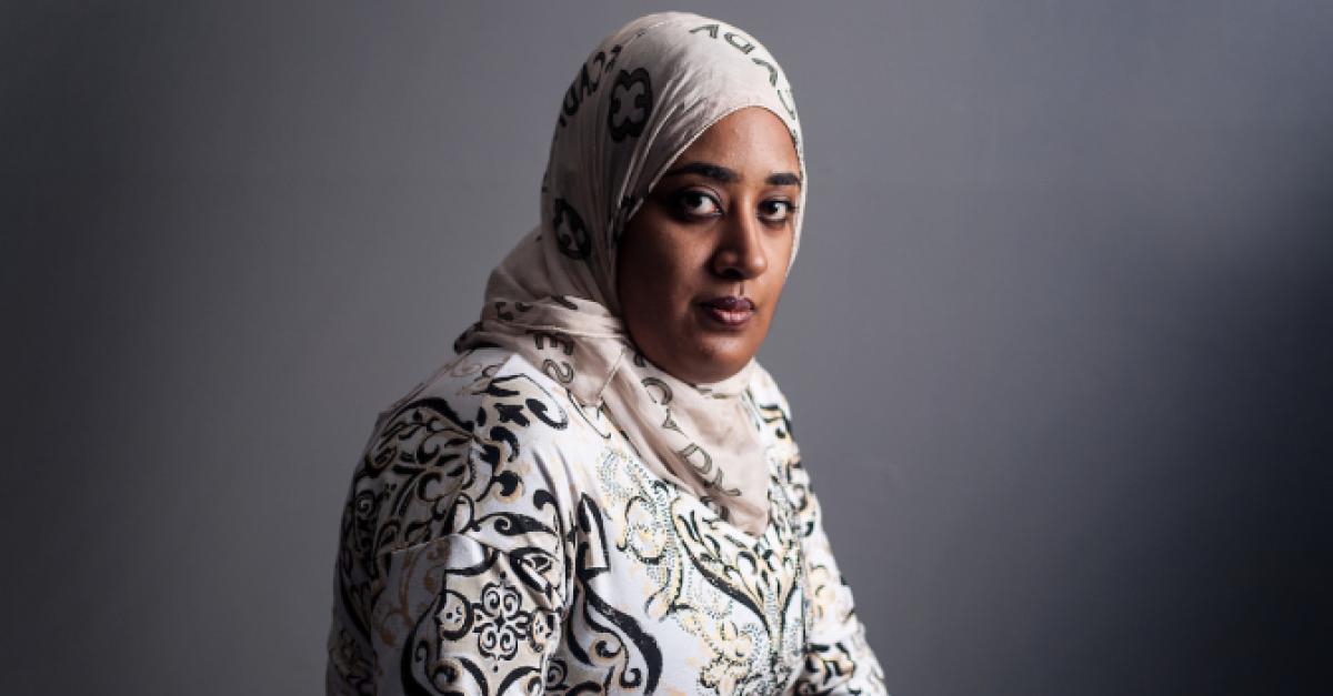 A portrait of a woman wearing a white hijab and dress.