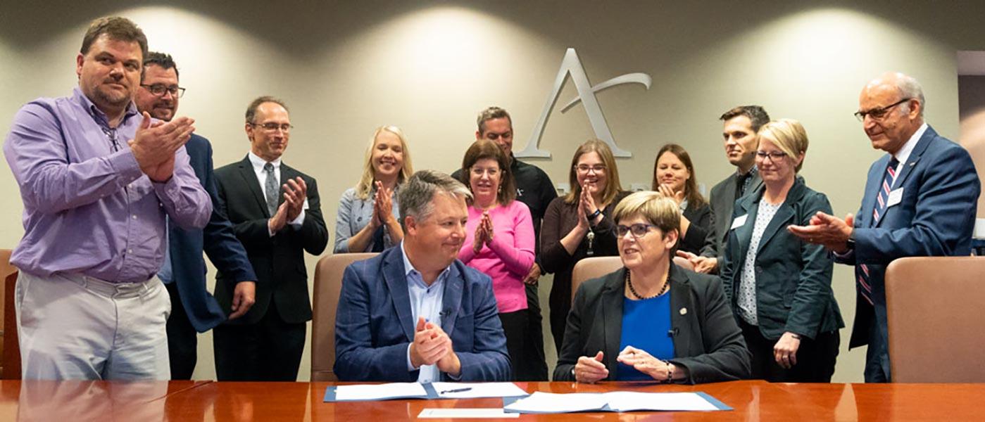 Metropolitan State University President Virginia “Ginny” Arthur (seated, right) and Affinity Plus Credit Union President and CEO Dave Larson (seated, left) after signing the agreement to begin offering Metropolitan State MBA cohorts to Affinity Plus employees.