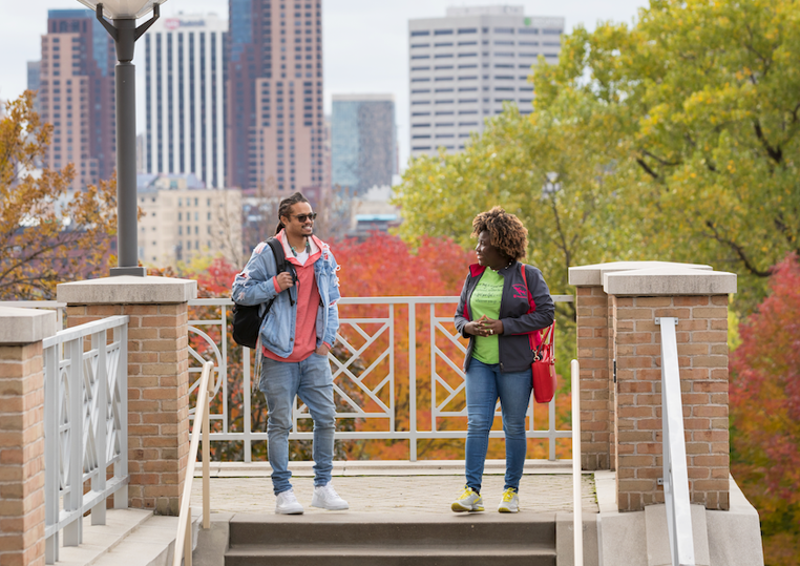 Two people talk at the top of an outdoor stairway on the Saint Paul Campus of Metro State