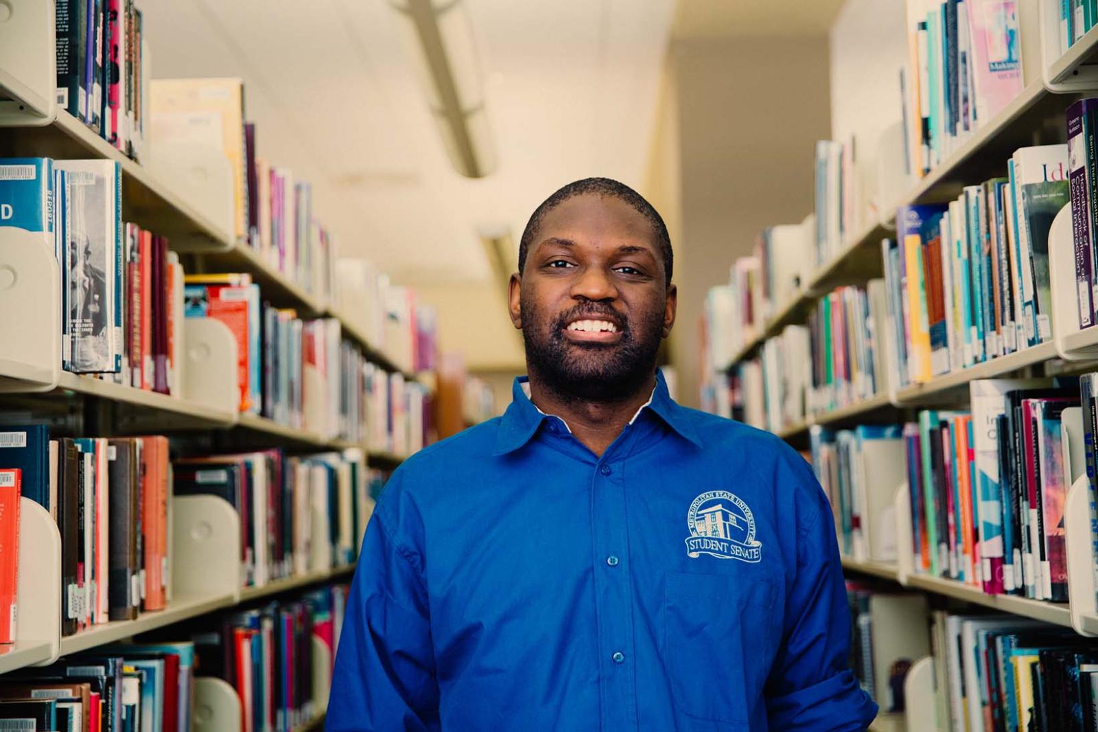 Student standing in library aisle