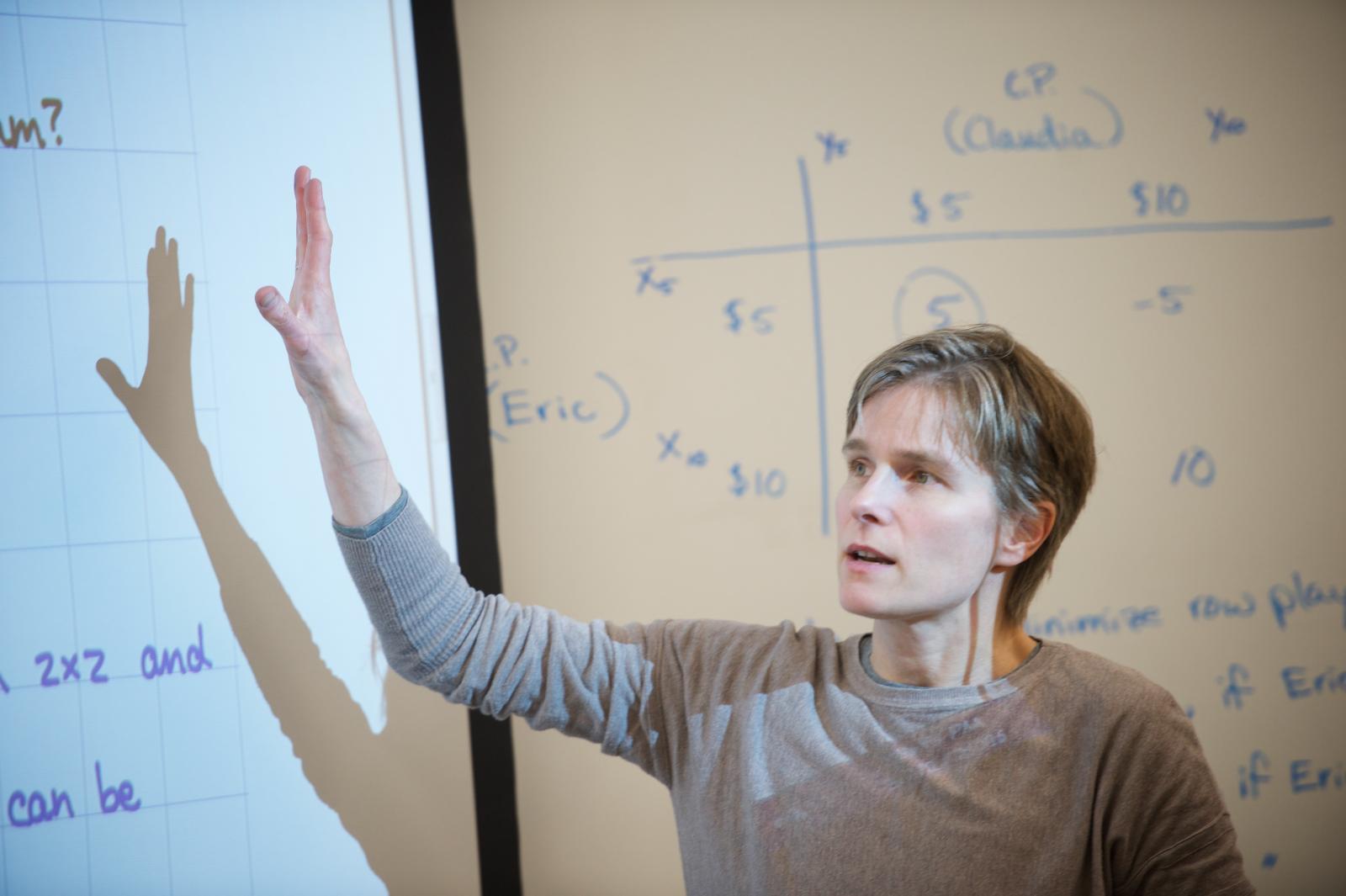 Instructor gestures toward equation on screen