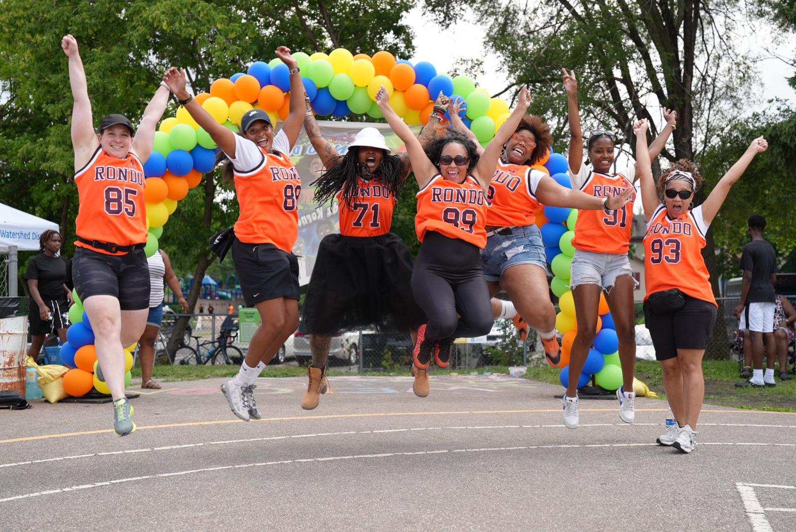 Members of Rondo Double Dutch jumping together in front of a balloon rainbow