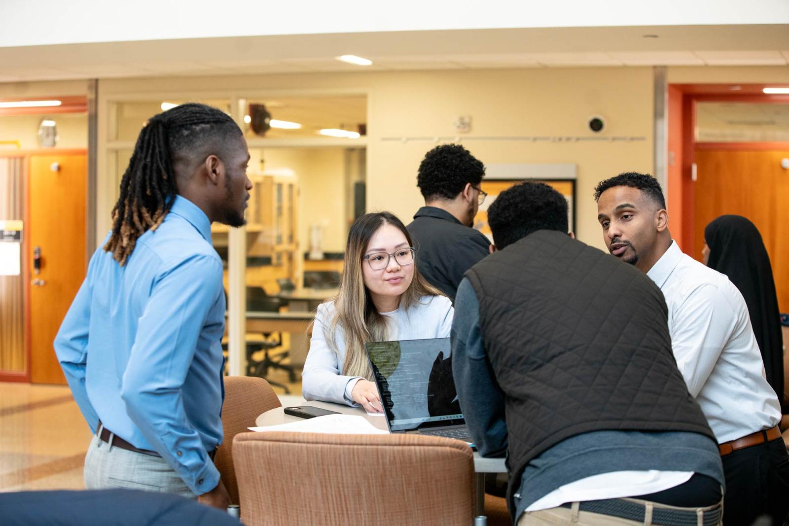 A group of students talk around a table. 