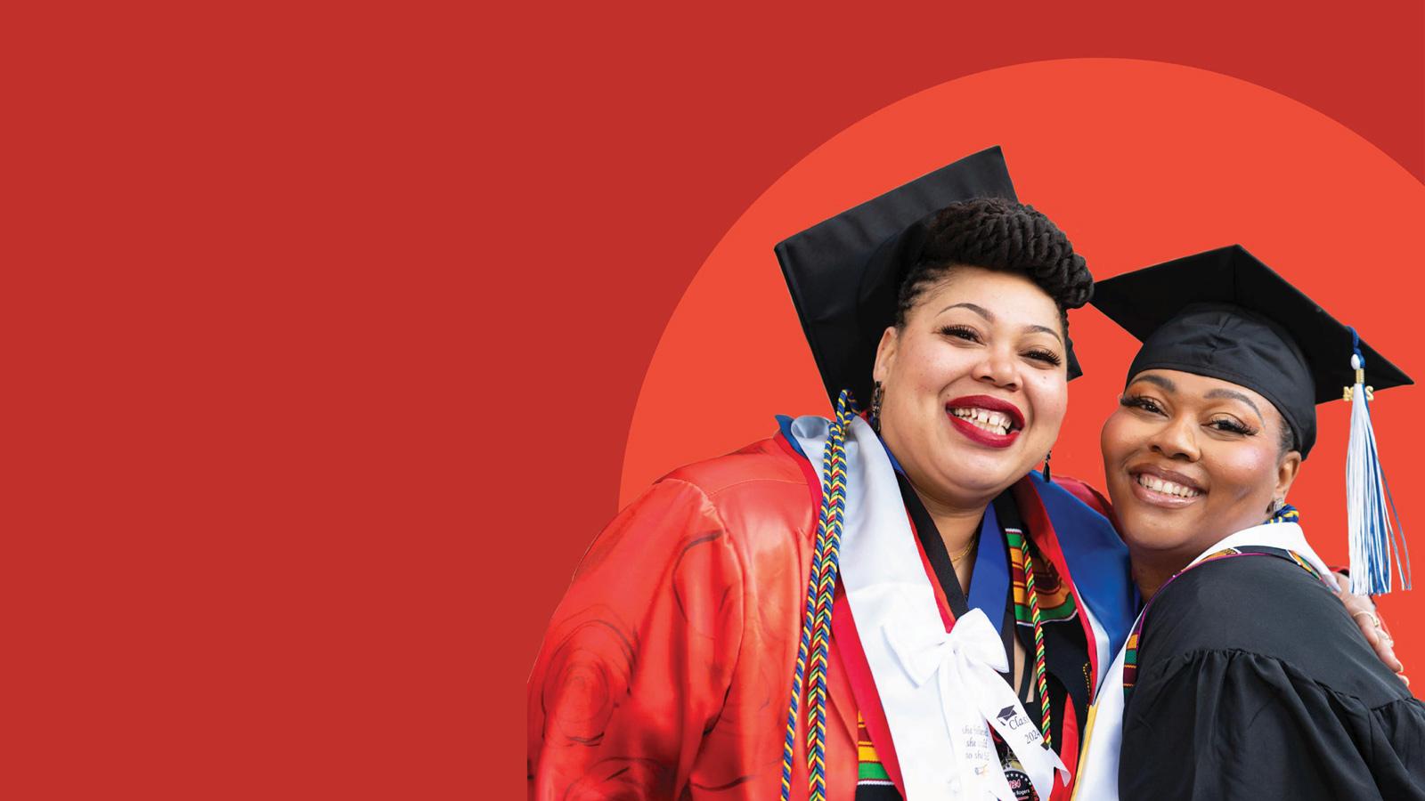 Two women pose in cap and gown against a red background