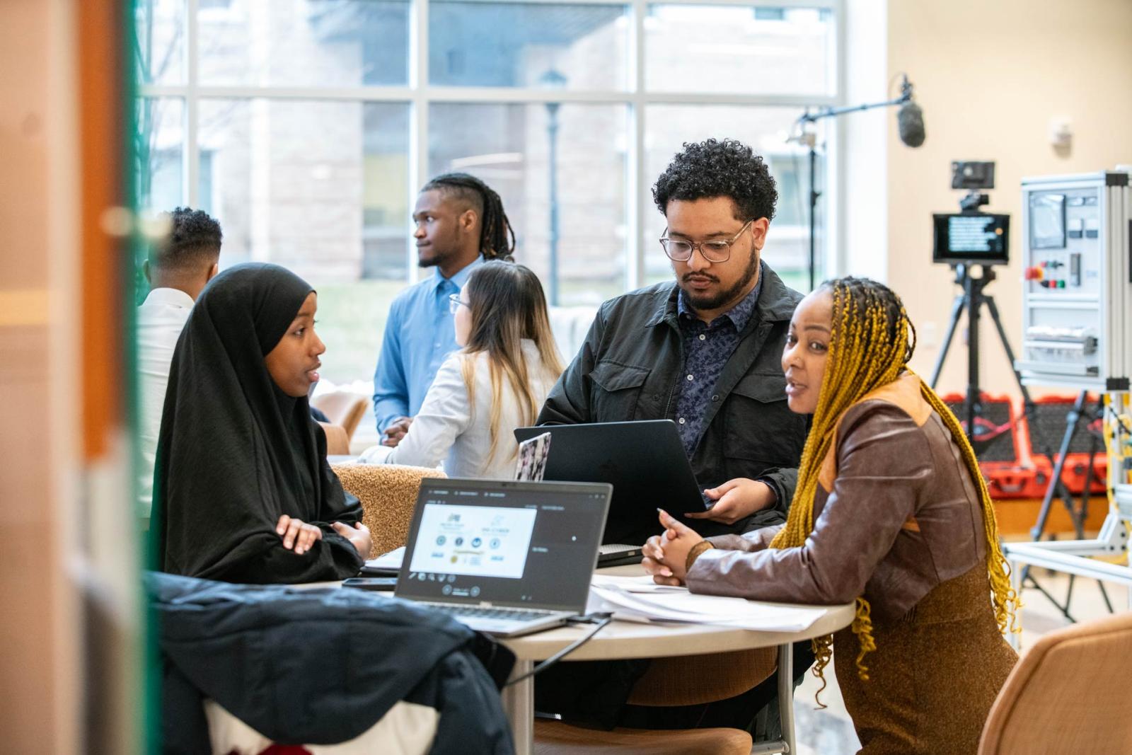 A group of students talking and working in a classroom