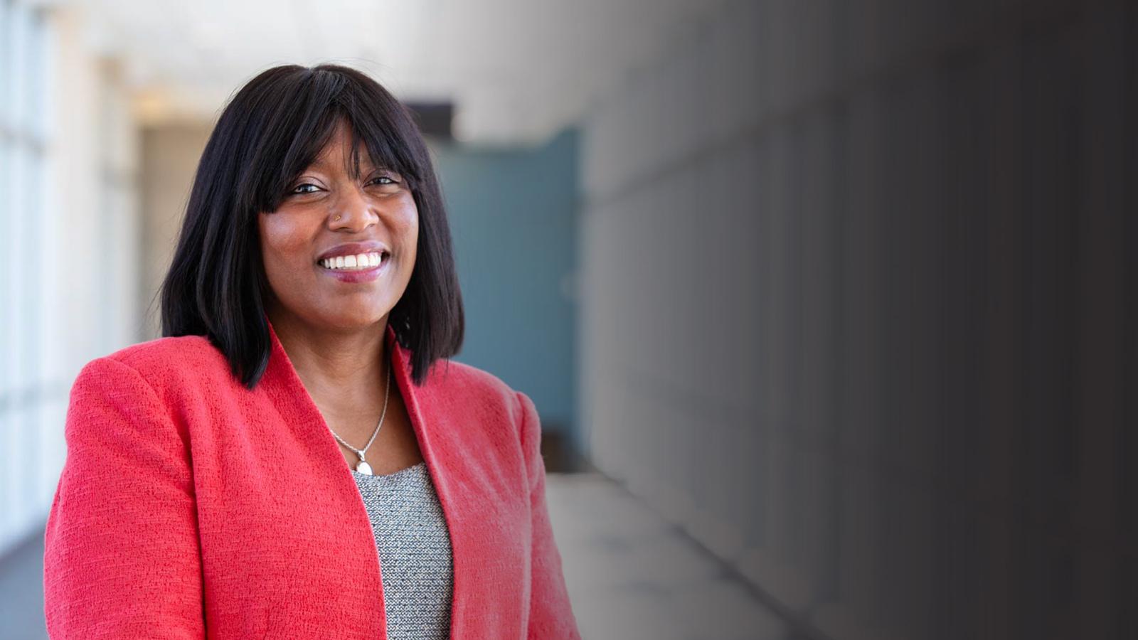 A woman in a salmon jacket poses for a picture