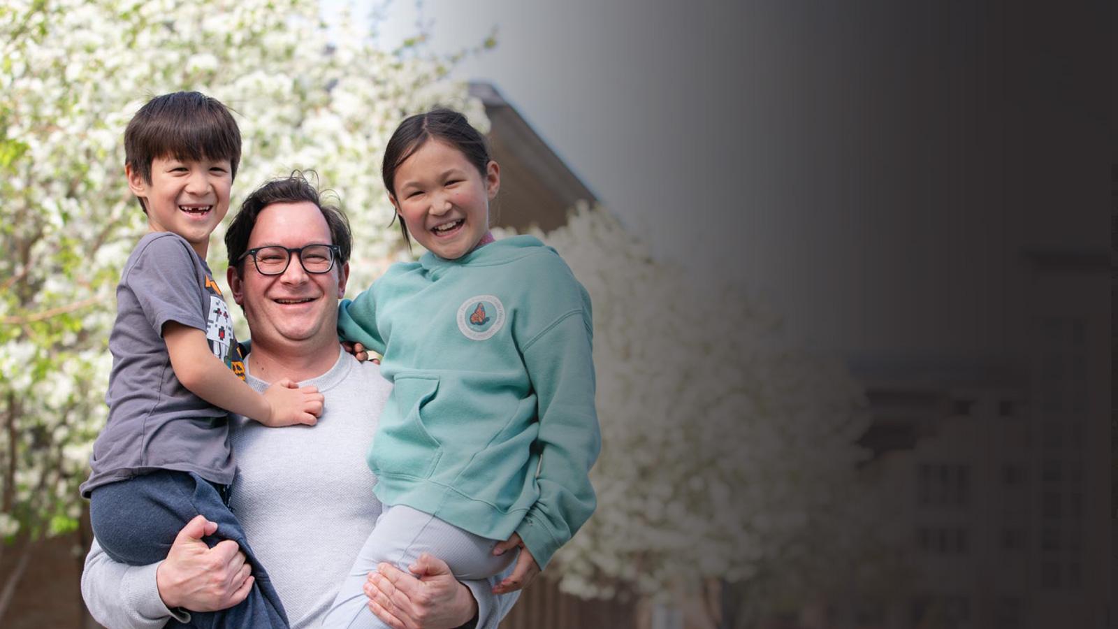 a person posing holding two children