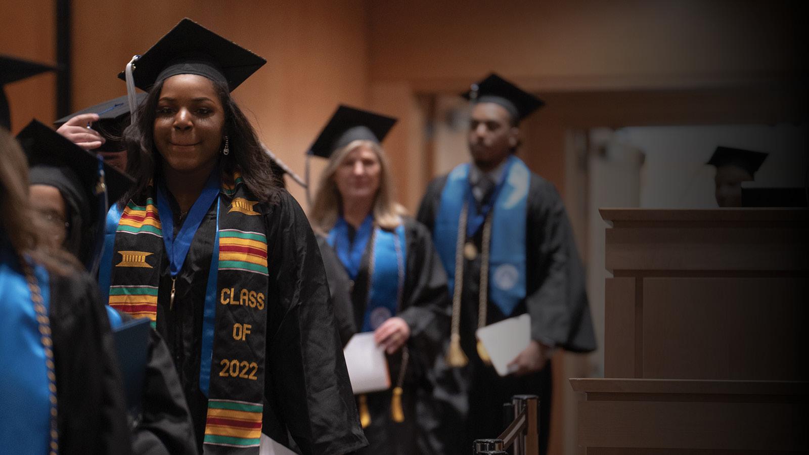 A line of people in cap and gown process during Commencement ceremonies