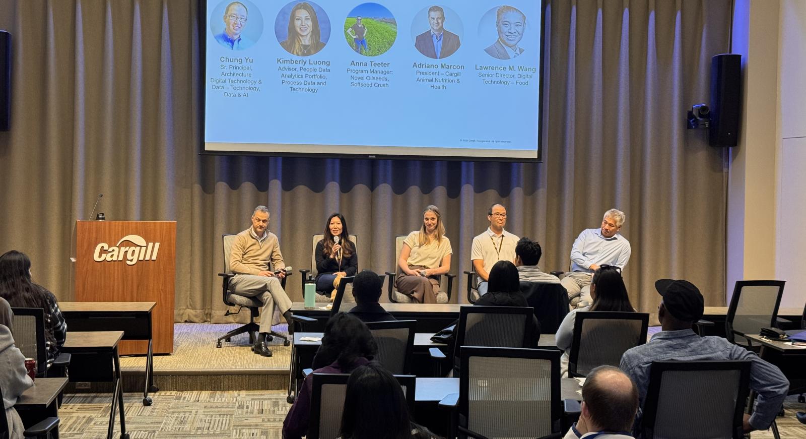 A group of people sit as a panel in a classroom