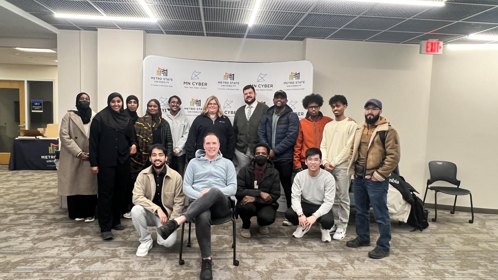 A group of people pose in front of the MN Cyber backdrop