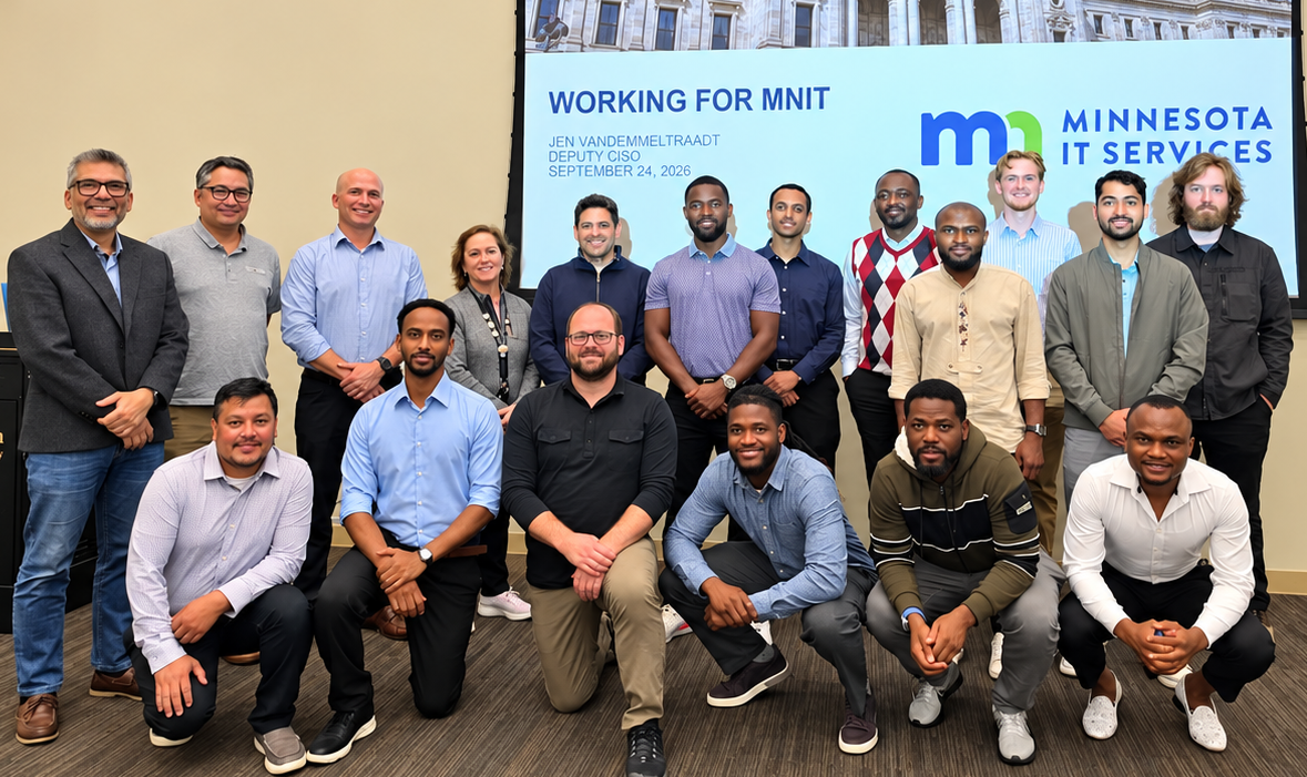 A large group photo in front of a screen saying Working for MNIT, Minnesota IT Services