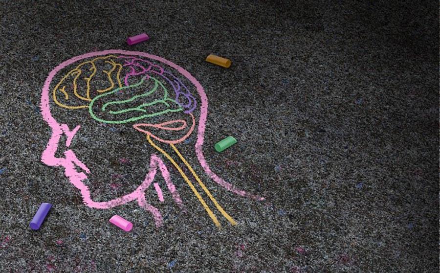 An illustration of an outline of a human head drawn in chalk on asphalt