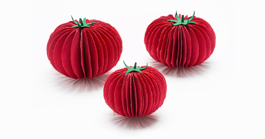 Three tomatoes made of handmade paper sitting on a white backdrop