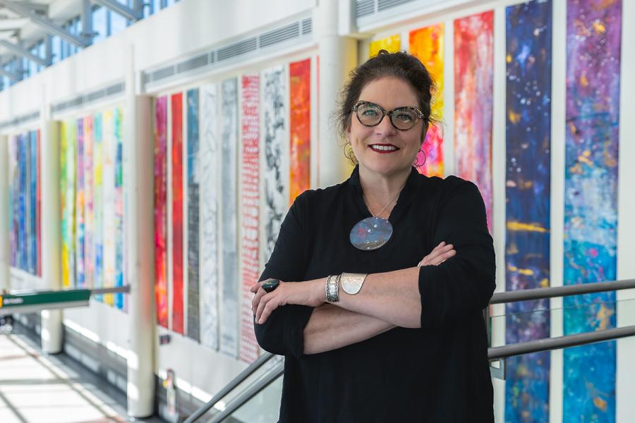 Minneapolis-based artist Anne Labovitz posing in front of a series of vertical colored banners