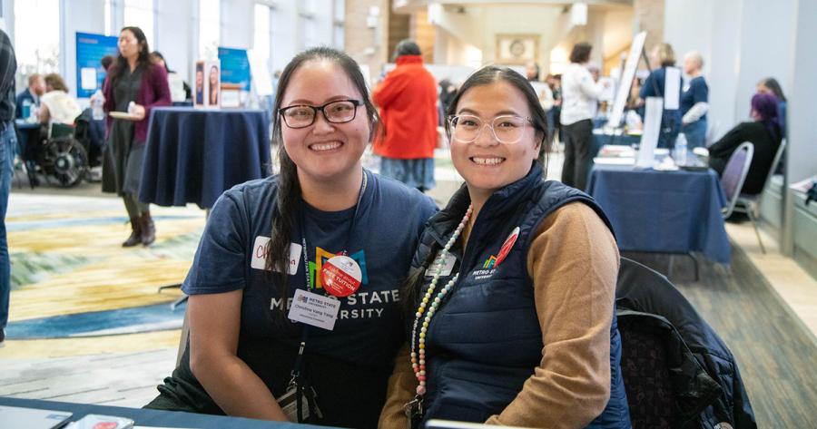 Two people pose for a photo sitting in the New Main Great Hall during an event