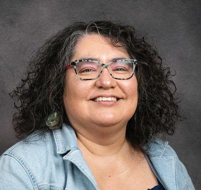 Rosalva Hernandez poses for a portrait in a light blue shirt and glasses