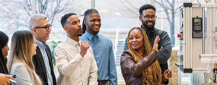 A group of people talk about a piece of equipment in a lab