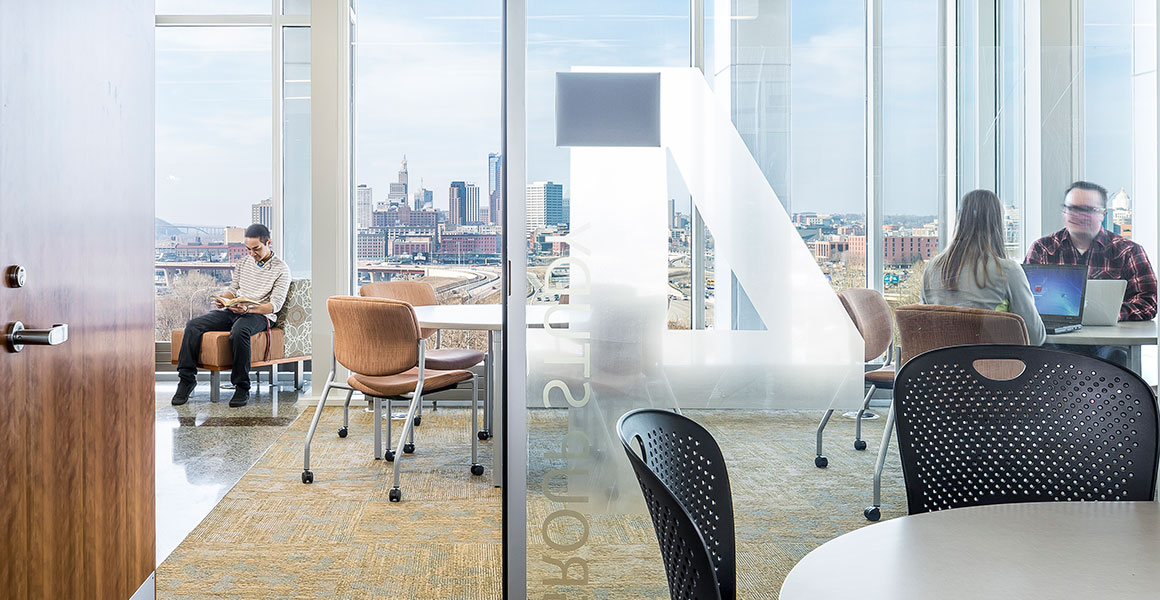 Students working in Group Study Room four in the Student Center on Metro State University’s Saint Paul campus, with the downtown Saint Paul skyline visible through the windows.