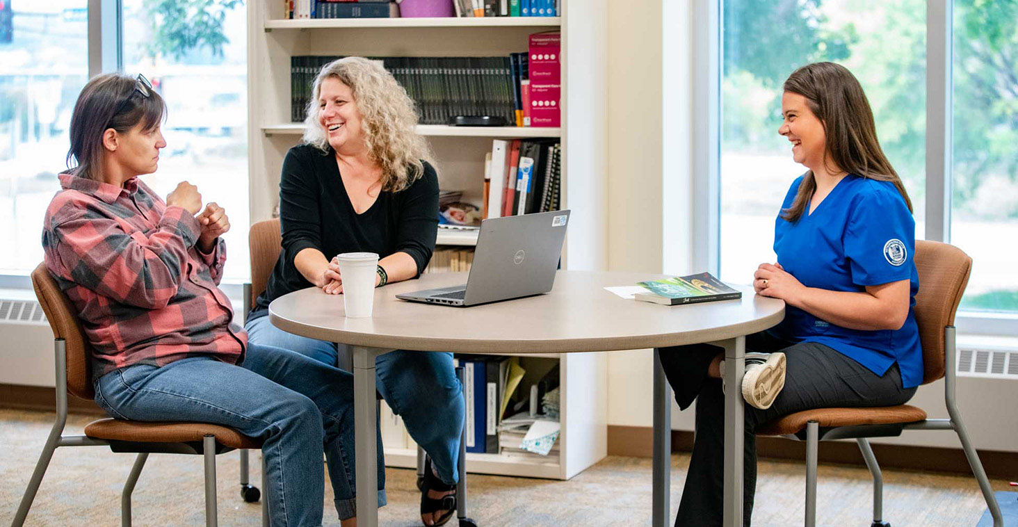 A Metro State student meets with a student and ASL staff member around a table in the Center for Accessibility Resources.